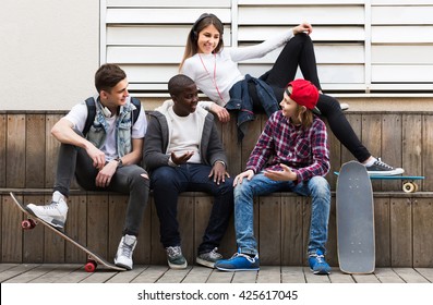 Smiling Girl And Three Boys Hanging Out Outdoors And Discussing Something 