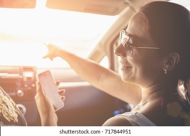 Smiling girl using gps navigator application on smartphone to navigate in car on holiday, toned - Shutterstock ID 717844951
