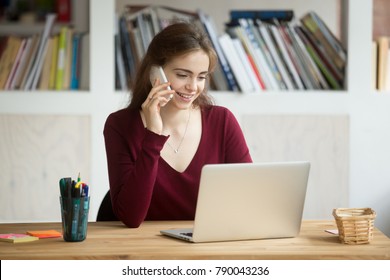 Smiling Girl Using Laptop Making Answering Call Sitting At Home Office Desk, Happy Student Talking On Phone Looking At Computer Screen, Young Sales Person Consulting Online Customer By Cellphone