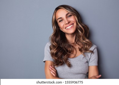 Smiling Girl With Wavy Long Hair. Portrait Happy Woman On Gray Background.