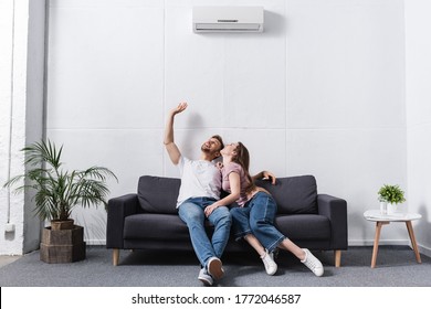 smiling girlfriend and boyfriend hugging at home with air conditioner