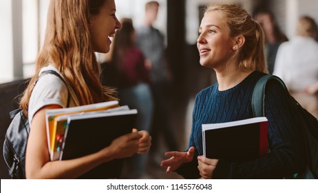 Smiling Girls In High School Corridor. Two Female College Students Talking After Lecture.