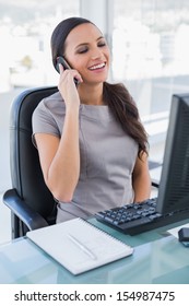 Lächelt eine wunderbare Geschäftsfrau am Telefon in ihrem Büro