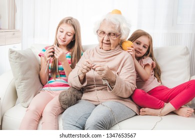 Smiling granddaughters with grandmother knitting together - Shutterstock ID 1347653567