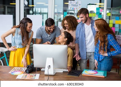 Smiling graphic designers interacting with each other while working at desk in office - Powered by Shutterstock