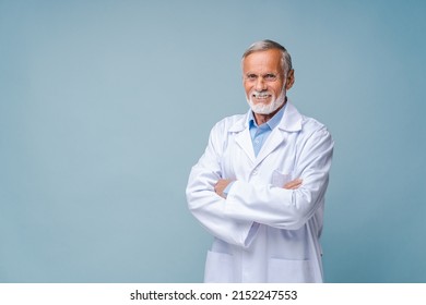 Smiling grey-haired male doctor, physical, therapist wearing white medical gown with stethoscope on shoulders stands with arms crossed isolated on blue, copy space. Healthcare and medicine - Powered by Shutterstock