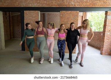 Smiling Group Of Attractive And Fit Female Friends Of Diverse Body Types In Sportswear Walking Arm In Arm Together After A Workout Class In A Gym. High Quality Photo