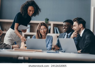 Smiling group of business people discussing strategy during team meeting at the office desk together - Powered by Shutterstock