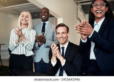 Smiling Group Of Diverse Businesspeople Clapping While Watching A Presentation Together In An Office