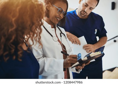 Smiling group of diverse doctors reading a patient's notes together while standing in the corridor of a hospital