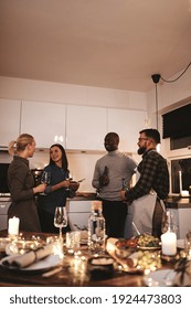 Smiling Group Of Diverse Friends Talking And Having Drinks Together In A Kitchen During An Evening Dinner Party