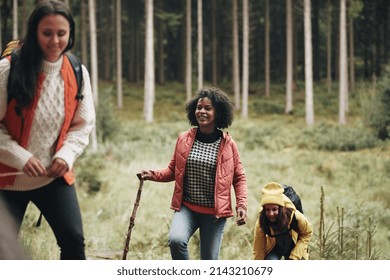 Smiling Group Of Diverse Young Female Friends In Outdoor Gear Hiking Up A Hill Together In The Woods