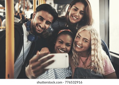 Smiling group of diverse young friends riding on a bus taking selfies together with a smartphone - Powered by Shutterstock