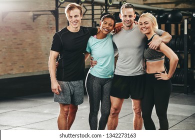 Smiling Group Of Fit Friends In Sportswear Standing Arm In Arm Together After A Workout Class In A Gym