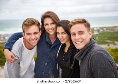 Smiling group of friends standing outdoors on a nature trail posing for a picture