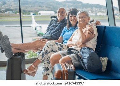 Smiling group of senior friends sitting in airport departure area waiting for boarding. Travel and tourism concept, retiree lifestyle - Powered by Shutterstock