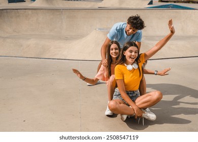 Smiling group of teenagers high school pupils friends classmates college students boys girls have fun on skateboard boy pushing girl to ride in skate park ramp urban street. Summer holidays concept - Powered by Shutterstock