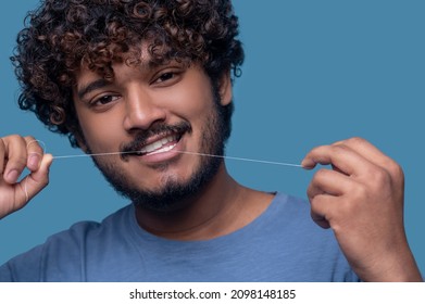 Smiling Guy With Curly Hair Flossing His Teeth