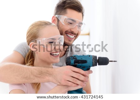 Smiling guy and girl making hole using drill