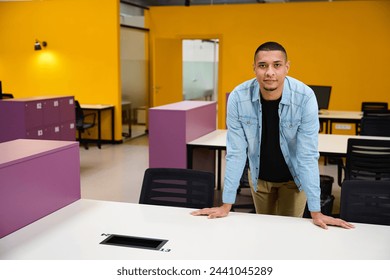 Smiling guy standing in office while leaning on table