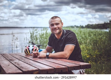 Smiling Guy At The Table Near Big Lake.