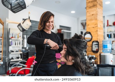 A smiling hairdresser straightens a client's hair in a bright, well-equipped salon with various hair care products and tools. - Powered by Shutterstock