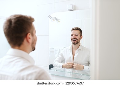 Smiling Handsome Businessman Dressing Up For Work While Standing In The Bathroom In Front Of Mirror.