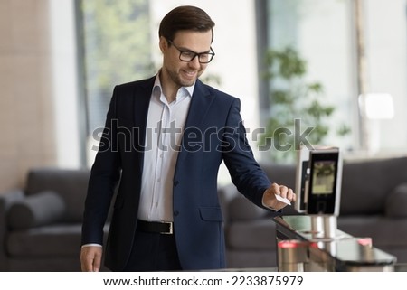 Smiling handsome businessman in suit swipe pass card to electronic reader, opening automatic gates, passing security system checkpoint leaves modern office area after working day. Door access, workday