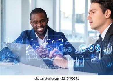 Smiling handsome businessmen wearing formal suits sitting typing on laptop with forex hologram graphs and chart in background. Concept of successful business person, trading on stock market, coworking - Powered by Shutterstock