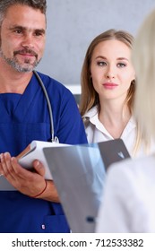 Smiling Handsome Doctor Communicate With Patient Holding Silver Pen And Showing Pad. Physical Agreement Signature, Disease Prevention, Interpreter, Translator, Prescribe Remedy, Healthy Lifestyle