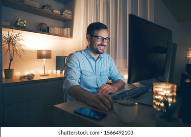 Smiling handsome freelancer working remotely from home at night.  - Shutterstock ID 1566492103