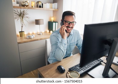 Smiling handsome freelancer working remotely from home. He is speaking on the phone. - Shutterstock ID 1567504015