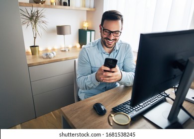 Smiling Handsome Freelancer Working Remotely From Home. He Is Using Phone.