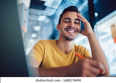 Smiling Handsome Male Student Enjoying Learning Process Making Notes For Homework,portrait Of Successful Smart Man Journalist Satisfied With Job Writing Article In Cafe Interior For Publication
