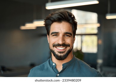 Smiling handsome young business man looking at camera in office, headshot close up corporate portrait. Happy Latin businessman, male entrepreneur, professional manager or company employee at work. - Powered by Shutterstock