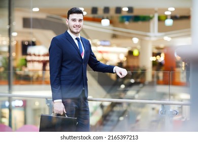 Smiling Handsome Young Male Property Manager Of Shopping Mall Leaning On Railing And Holding Briefcase While Looking At Camera