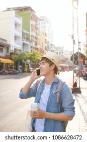 Smiling handsome young man drinking coffee and using smart phone