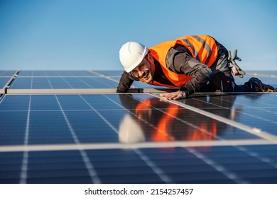A smiling handyman looking at solar panels if they are properly installed. - Shutterstock ID 2154257457