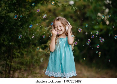 Smiling Happiness Child Enjoy Music In Big White Headphones .A Little Girl Shows A Sigh With Had Of Successful