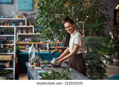 Smiling happy African American florist making a florarium