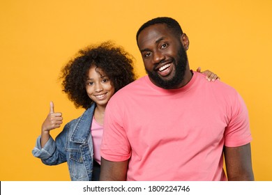 Smiling happy african american man and little kid girl, big brother sister standing behind in denim pink clothes hugging, showing thumbs up isolated on yellow background studio portrait. - Powered by Shutterstock