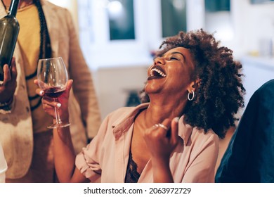 smiling happy african lady at table - african american woman laughing at party - young female person holding glass of wine at dinner 