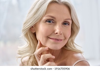 Smiling happy attractive 50s middle aged mature blond woman, old lady looking at camera advertising anti age face skin and body care treatment cosmetics posing in bathroom. Close up headshot portrait - Shutterstock ID 1916705906