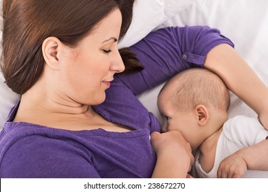 Smiling happy beautiful mother breastfeeding her baby infant