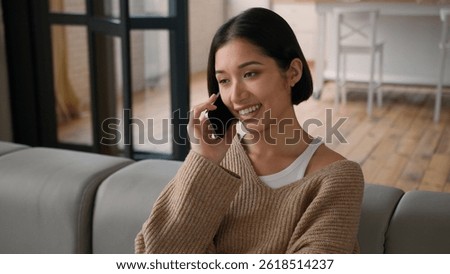 Smiling happy carefree Hispanic Caucasian woman female homeowner girl housewife tenant talk speak mobile phone laughing distant smartphone call friendly casual conversation at home discuss news gossip