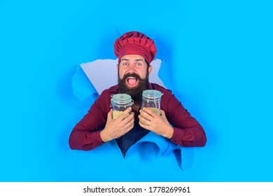 Smiling Happy Chef Man Holds Glass Jar With Raw Corn Grits. Cooking, Grits, Organic Food, Dieting, Healthy Food Cooking, Restaurant Concept - Professional Chef. Copy Space For Advertise Restaurant.