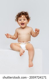 Niña feliz sonriente. Retrato de niño pequeño, bebé en pañal sentado alegremente y riendo aislado en el fondo blanco del estudio. Concepto de infancia, maternidad, vida, nacimiento. Copiar espacio para el anuncio