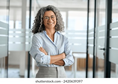 Smiling happy confident old mature professional business woman corporate leader, senior middle aged female executive, lady bank manager standing in office arms crossed looking at camera, portrait. - Powered by Shutterstock