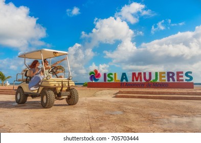 Smiling and happy couple driving a golf cart at tropical beach on Isla Mujeres, Mexico