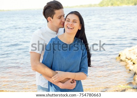 Smiling happy couple on sea. Couple in love, enjoying the summer time by the sea. Embrace the couple in love with the background of the river / sea.